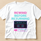 White T-shirt printed with the words Rewind Before Returning in neon letters above a home movies video tape, rewind arrows and a New Release tag